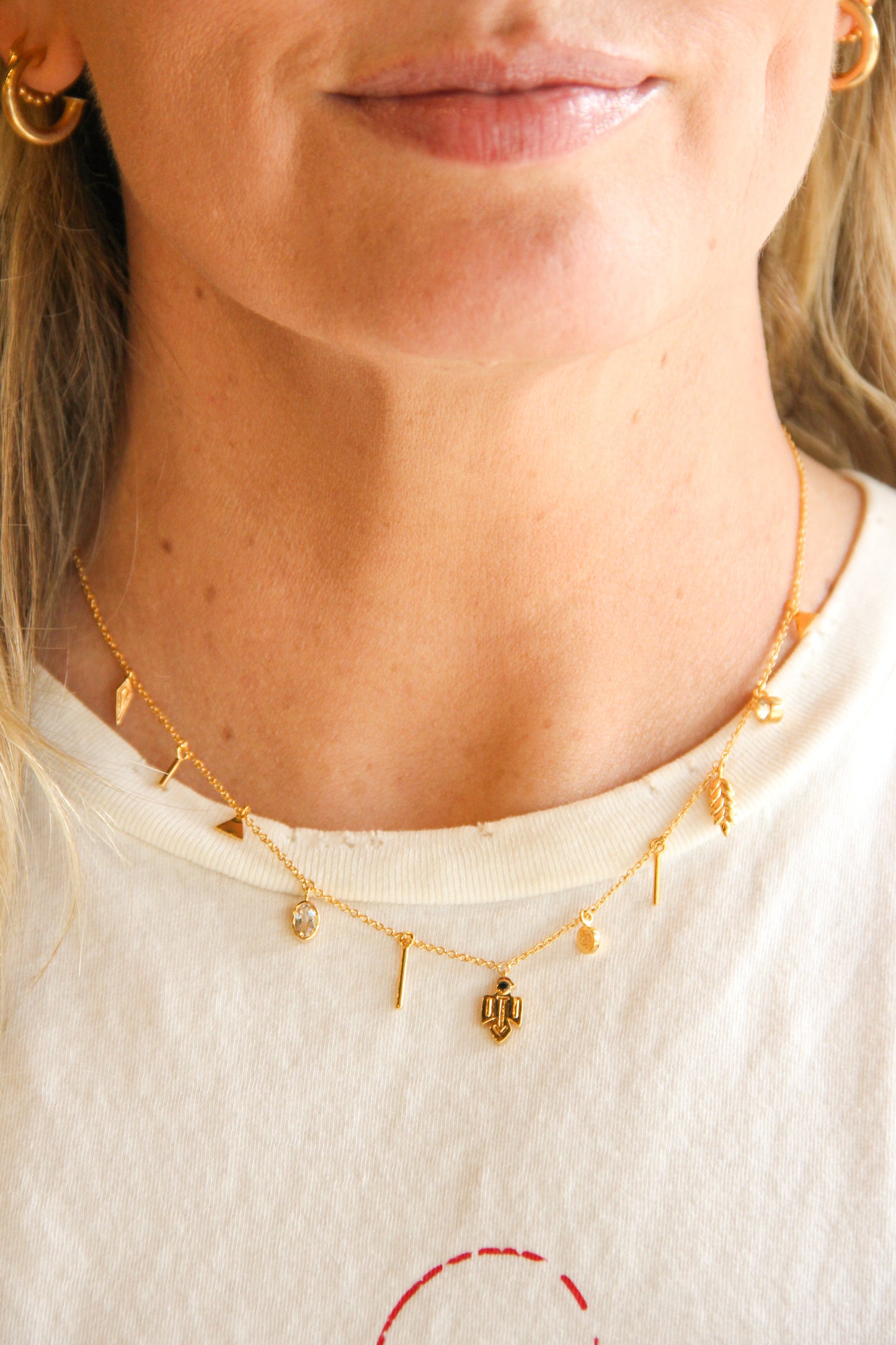 Close-up of a person wearing a gold necklace with various talisman pendants