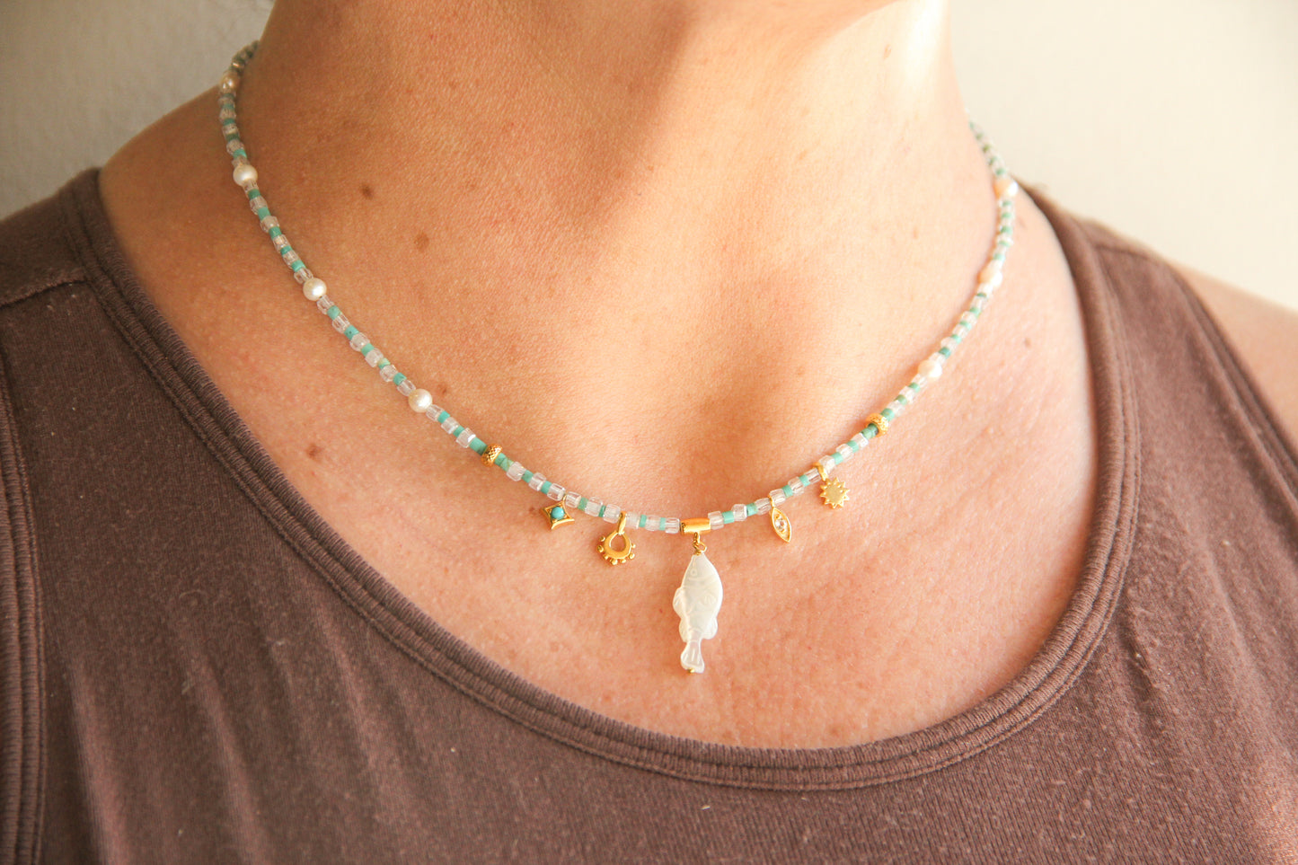 white topaz and turqoise beaded necklace with a carved mother of pearl fish charm