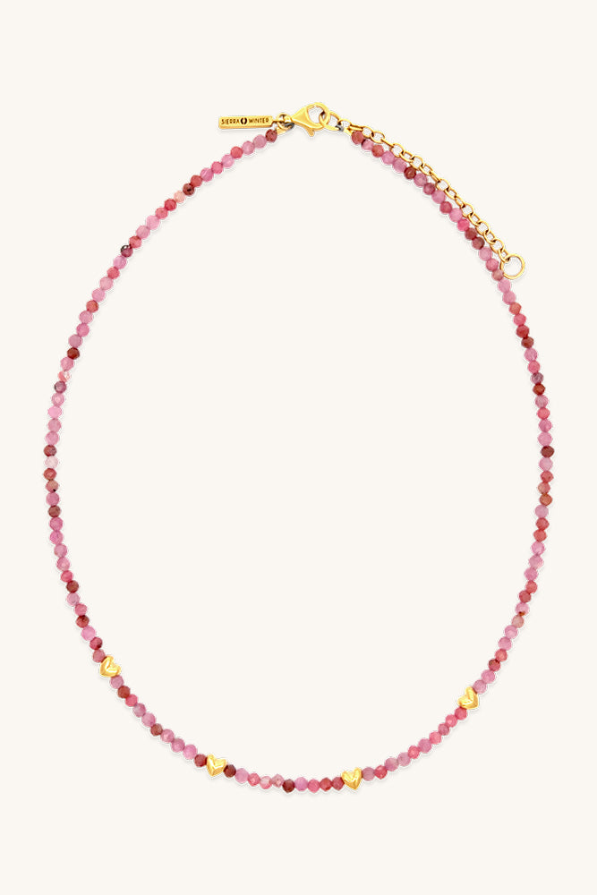 Necklace with pink beads and gold clasp on a white background